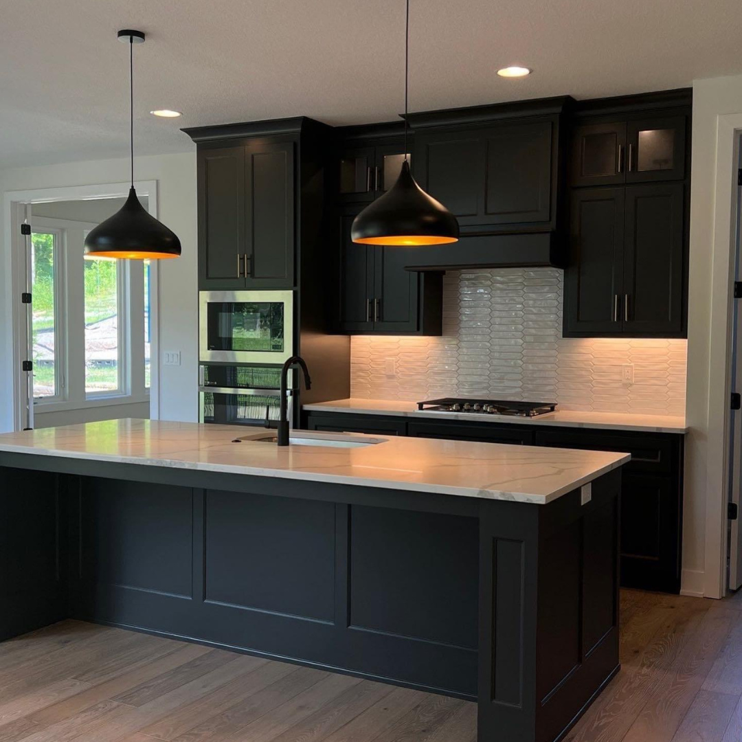 Kitchen island and cabinets painted black by Painters Pro KC with white tile backsplash and oak wood floors