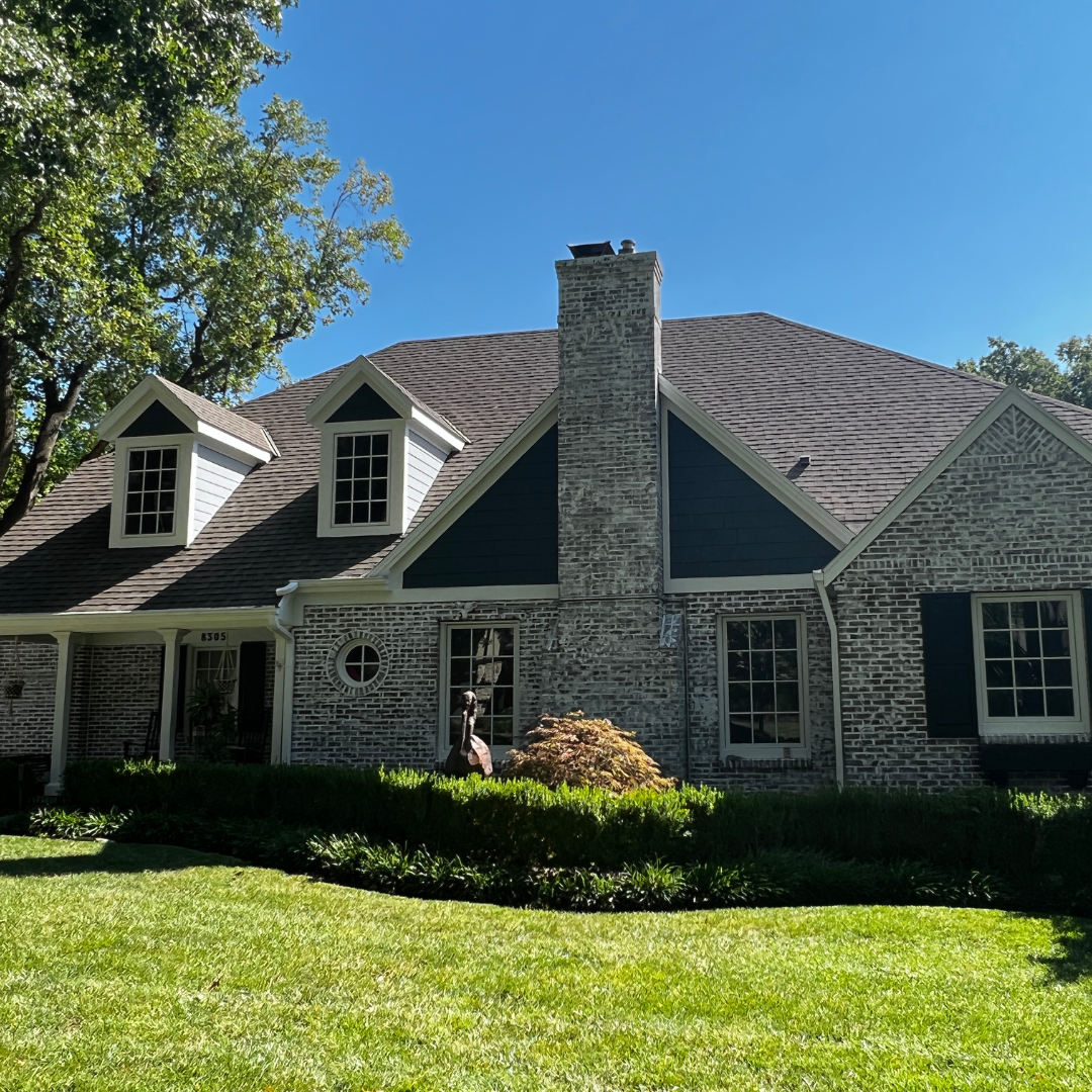 Exterior paint job on Kansas City home by Painters Pro KC, with rich blue shutters and dormers, and white trim on a brick house.