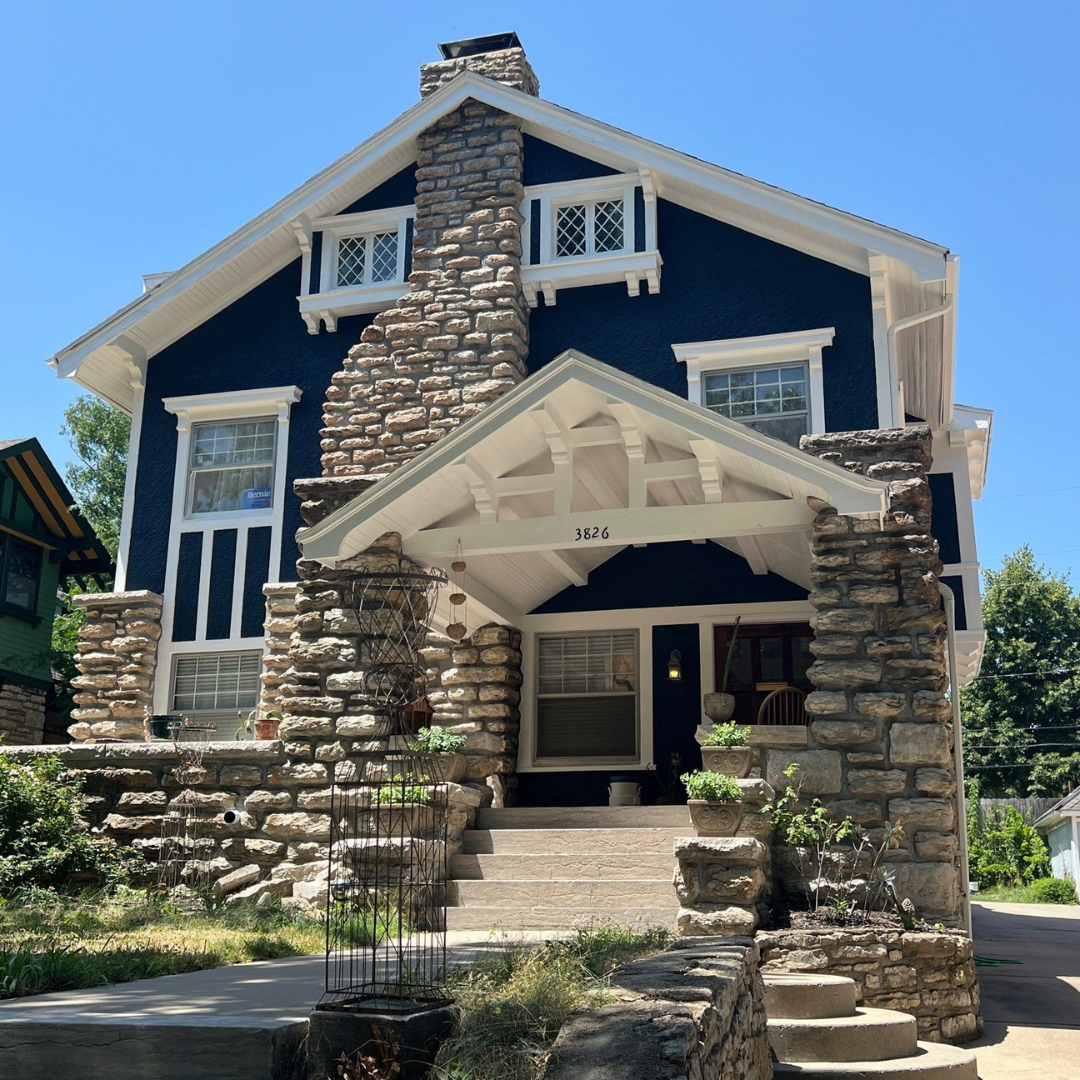 Exterior of a traditional shirtwaist home in Kansas City transformed by Painters Pro KC, featuring a dark blue core with white trim around ornate windows.