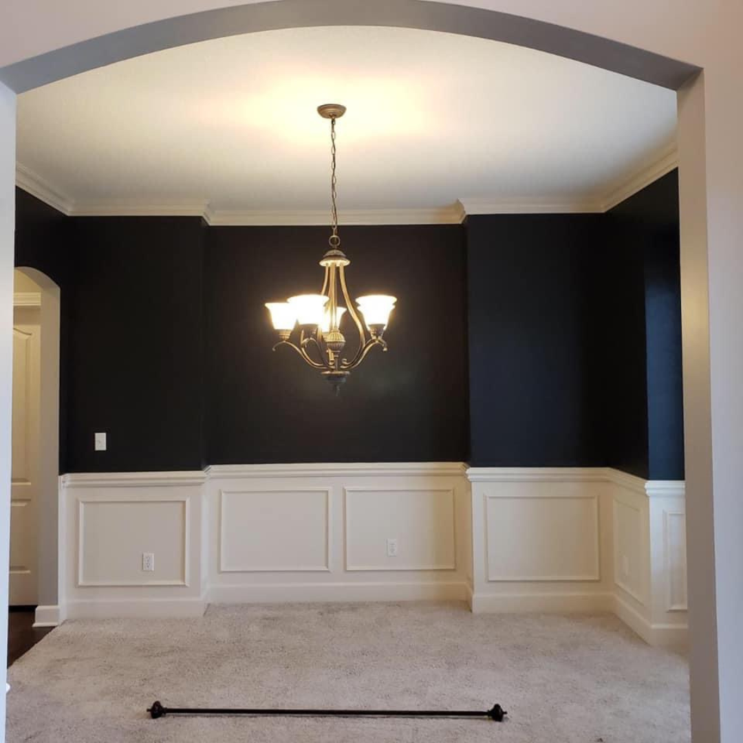 Interior dining room painted by Painters Pro KC, featuring dark blue upper walls and crisp white wood wainscoting, enhancing the room’s elegance.