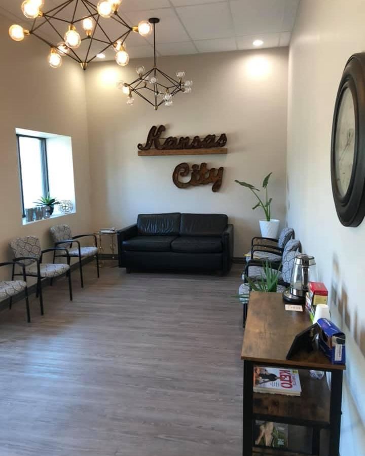 Waiting room of a Kansas City business with cream walls, Kansas City wood sign, couch, chairs, and hanging light fixtures.