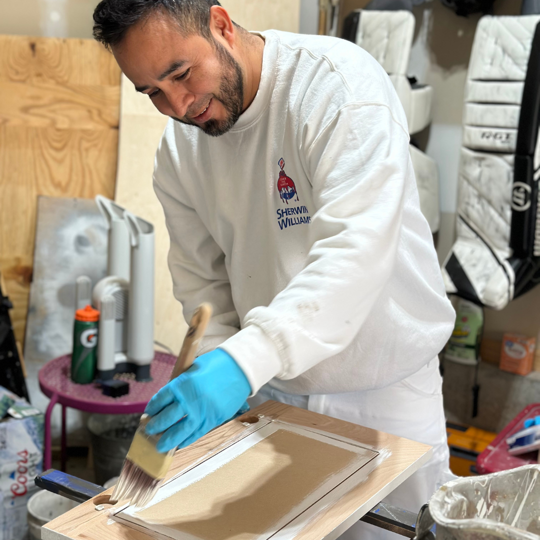 Painter from Painters Pro KC painting a cabinet door, smiling and focused.